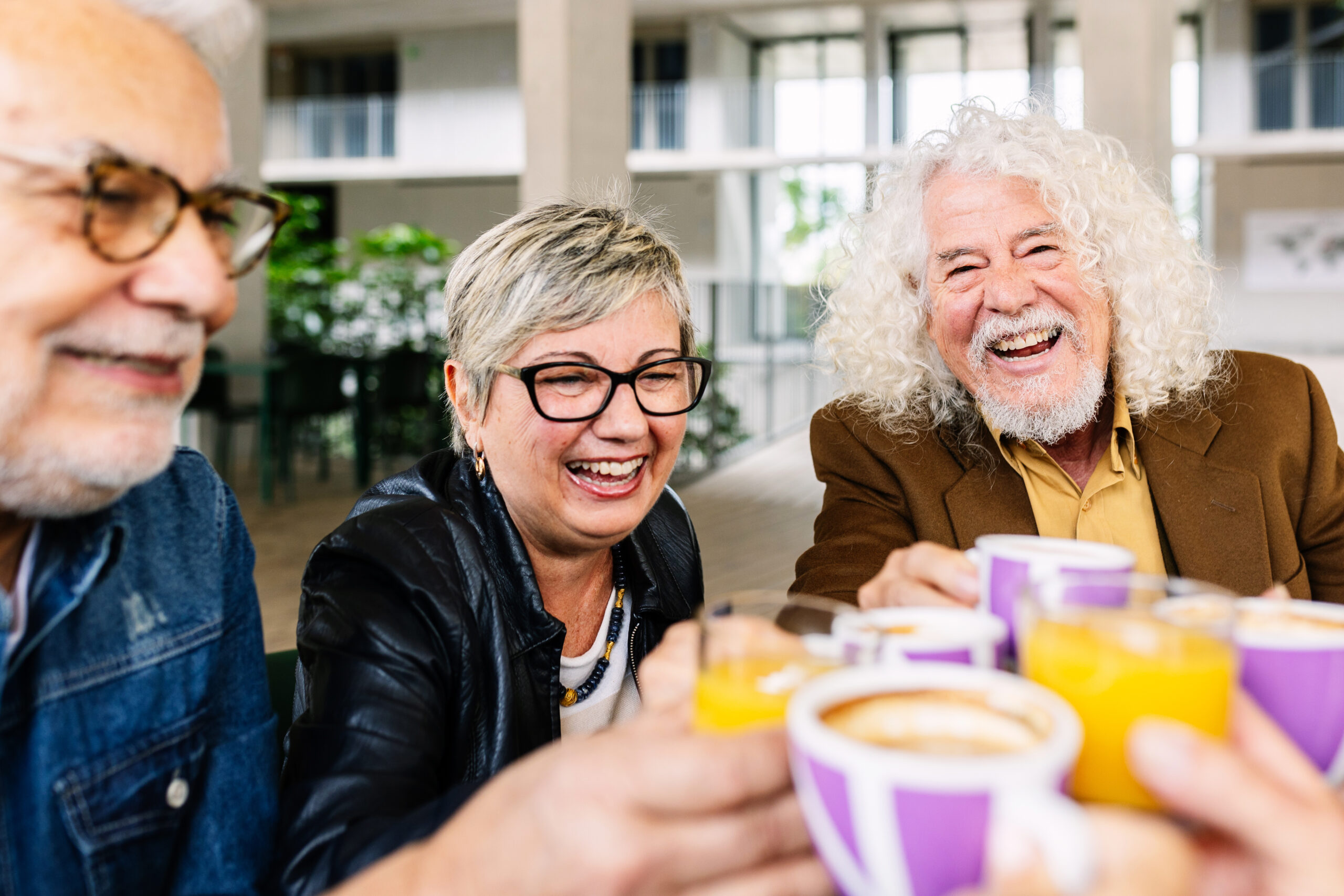 Happy young group of people having breakfast together at coffee bar