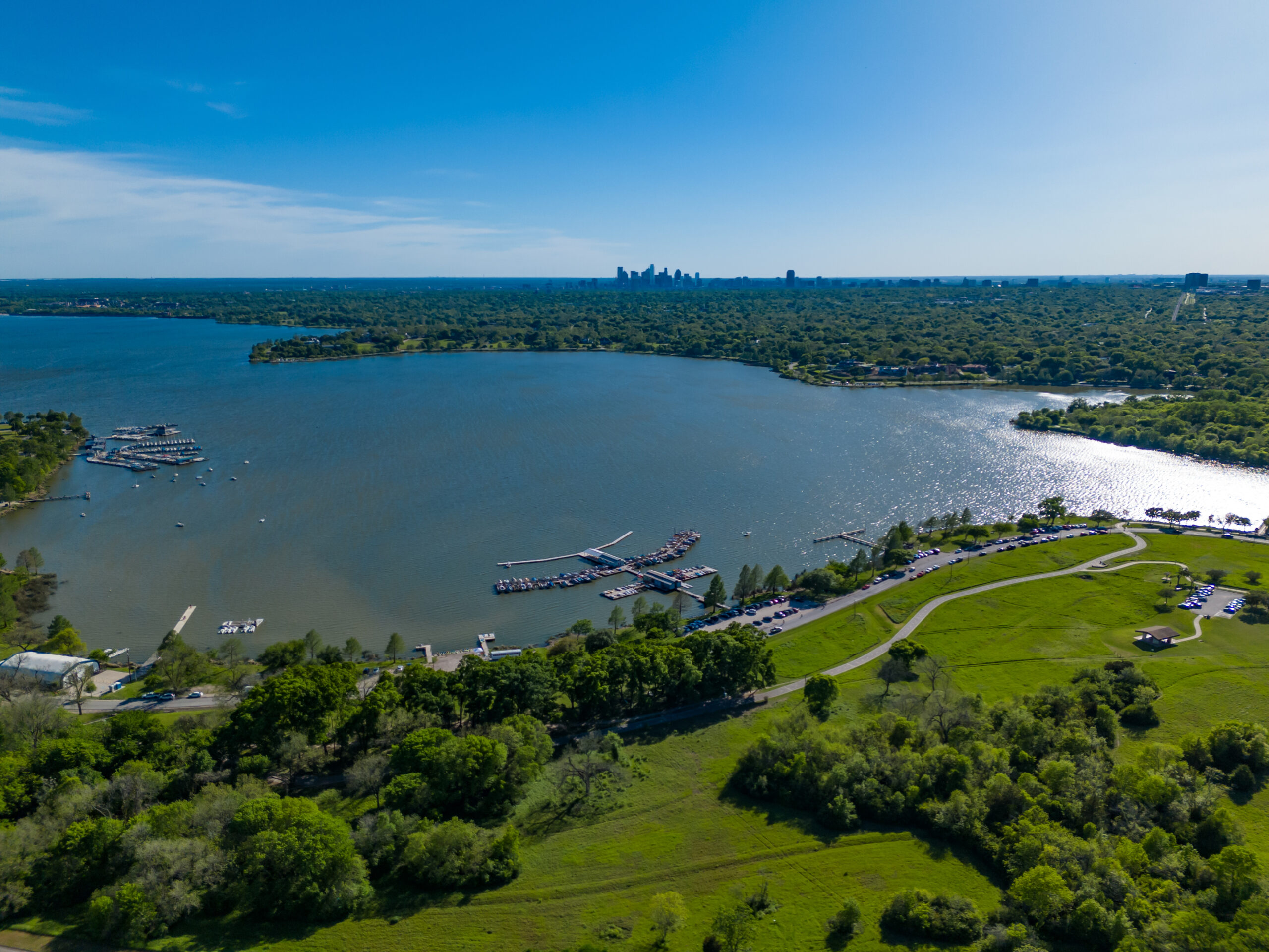 Dallas White Rock Lake Park and marina and Dallas skyline with blue sky and greenery