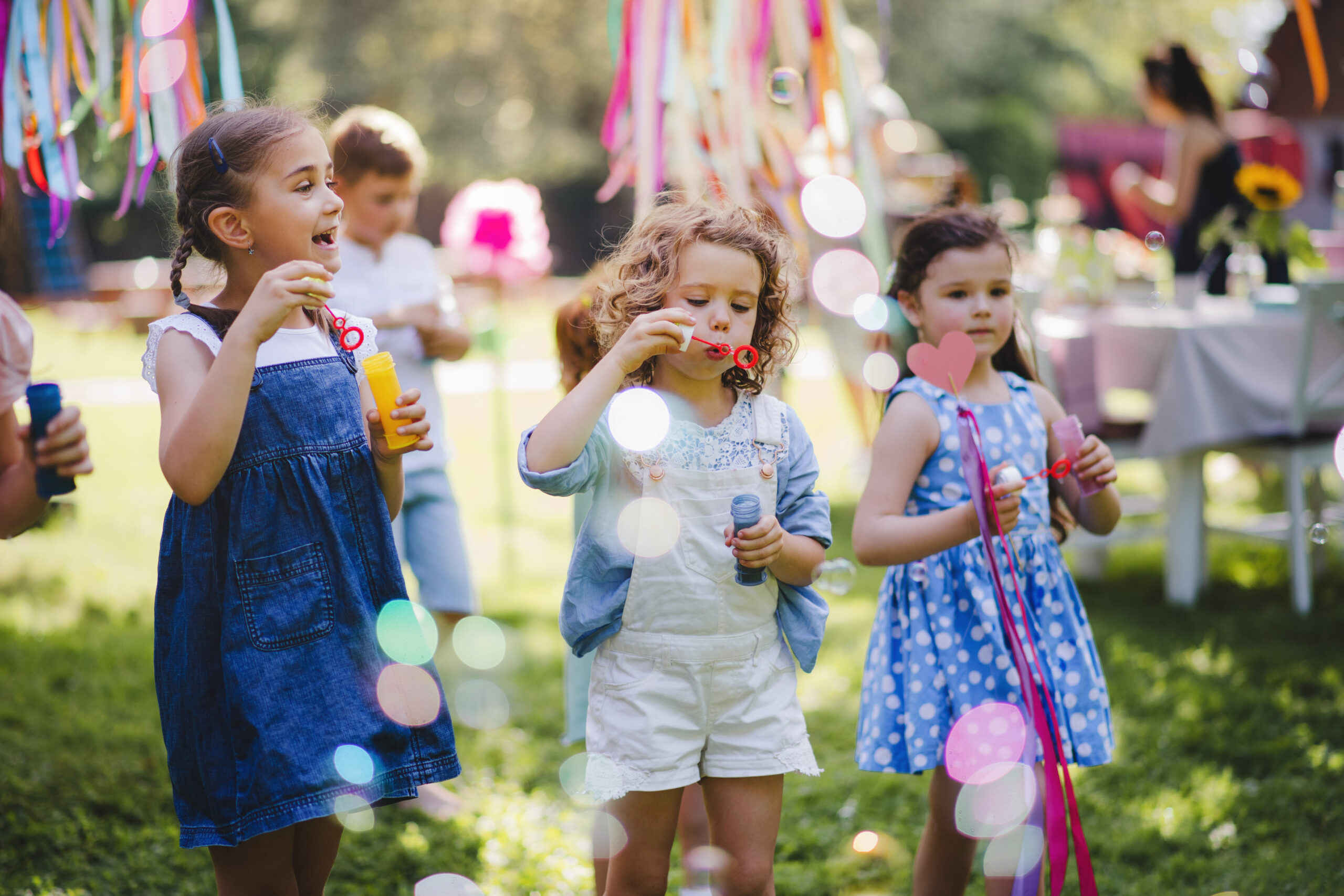 summer family reunion. Small children outdoors in garden in summer, playing with bubbles. summer family reunion. Small children outdoors in garden in summer, playing with bubbles. A celebration concept. summer family reunion