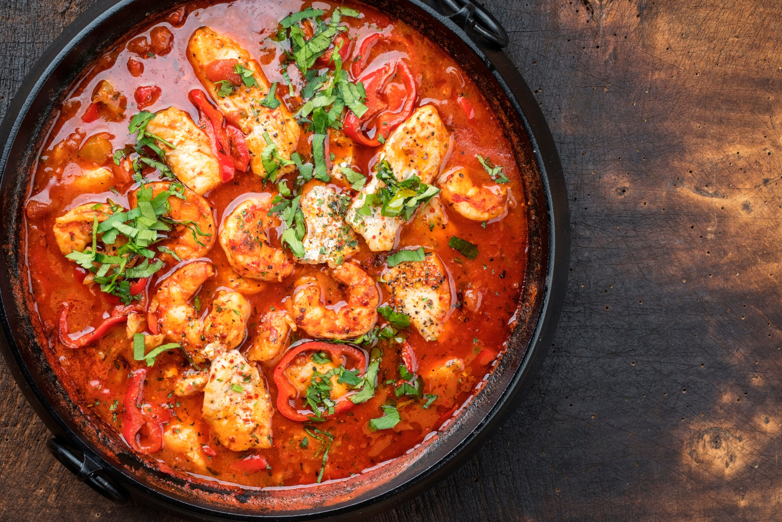 Traditional Creole cajun court bouillon with fish and seafood gumbo chowder stew as top view in a pot with copy space right. gumbo