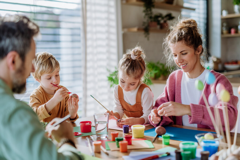 Happy family with little kids decorating easter eggs in their home. happy family doing crafts. holiday party ideas